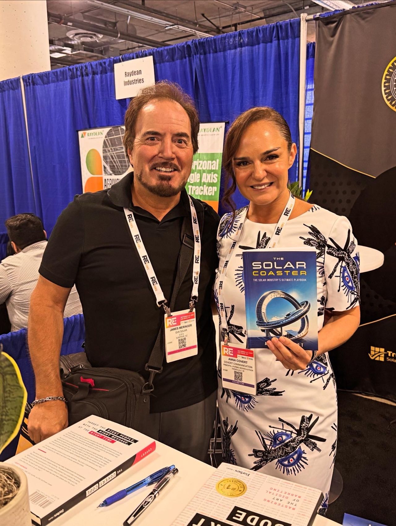 Anna Covert with James Bensinger at RE+ Las Vegas, holding The Solar Coaster book at The Covert Code booth
