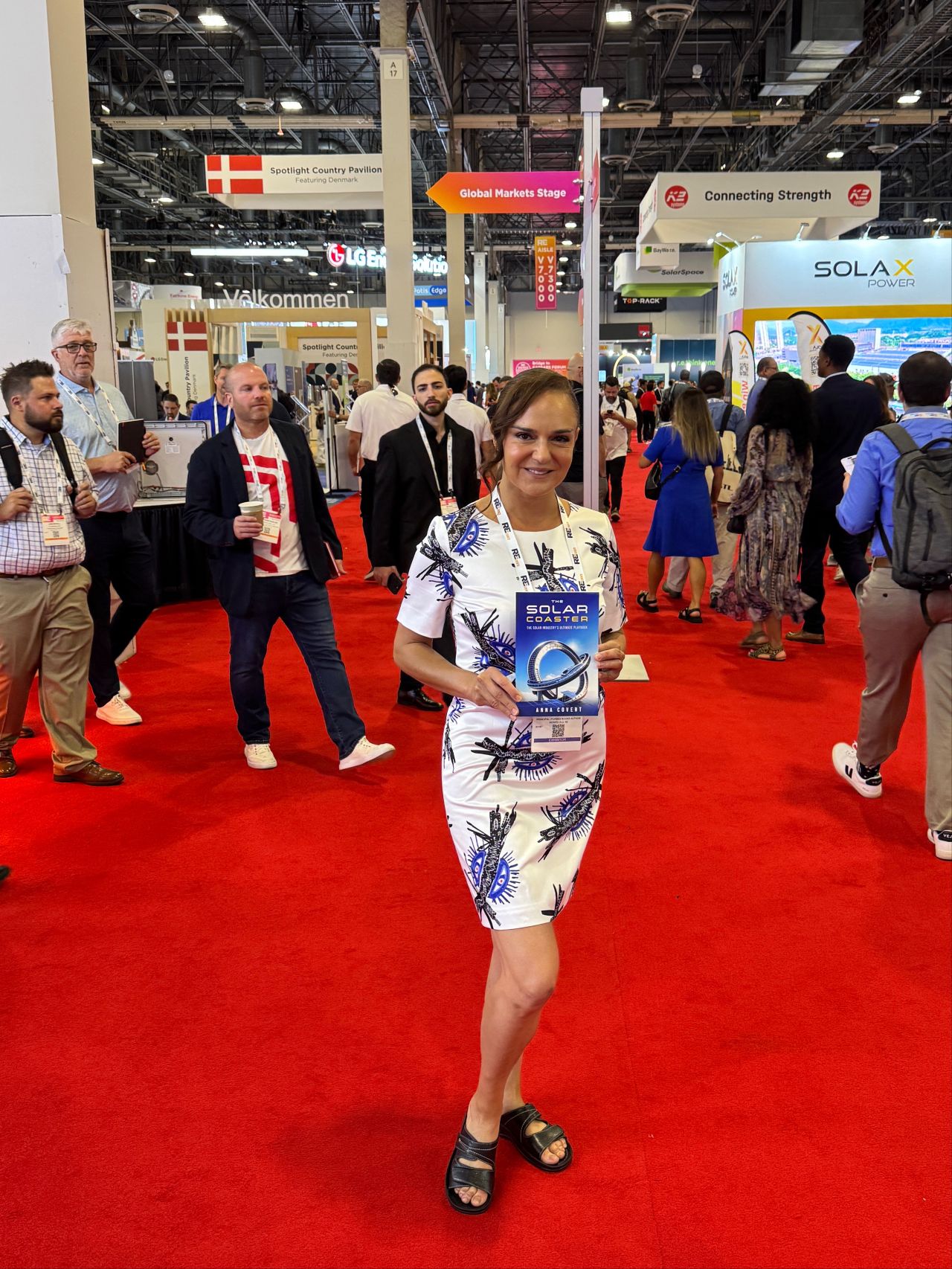 Anna Covert holding The Solar Coaster book on the red carpet at RE+ Las Vegas 2025, solar industry author and clean energy leader