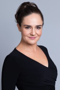 Anna Covert, author of The Covert Code and The Solar Coaster, professional headshot in black dress with gray backdrop.